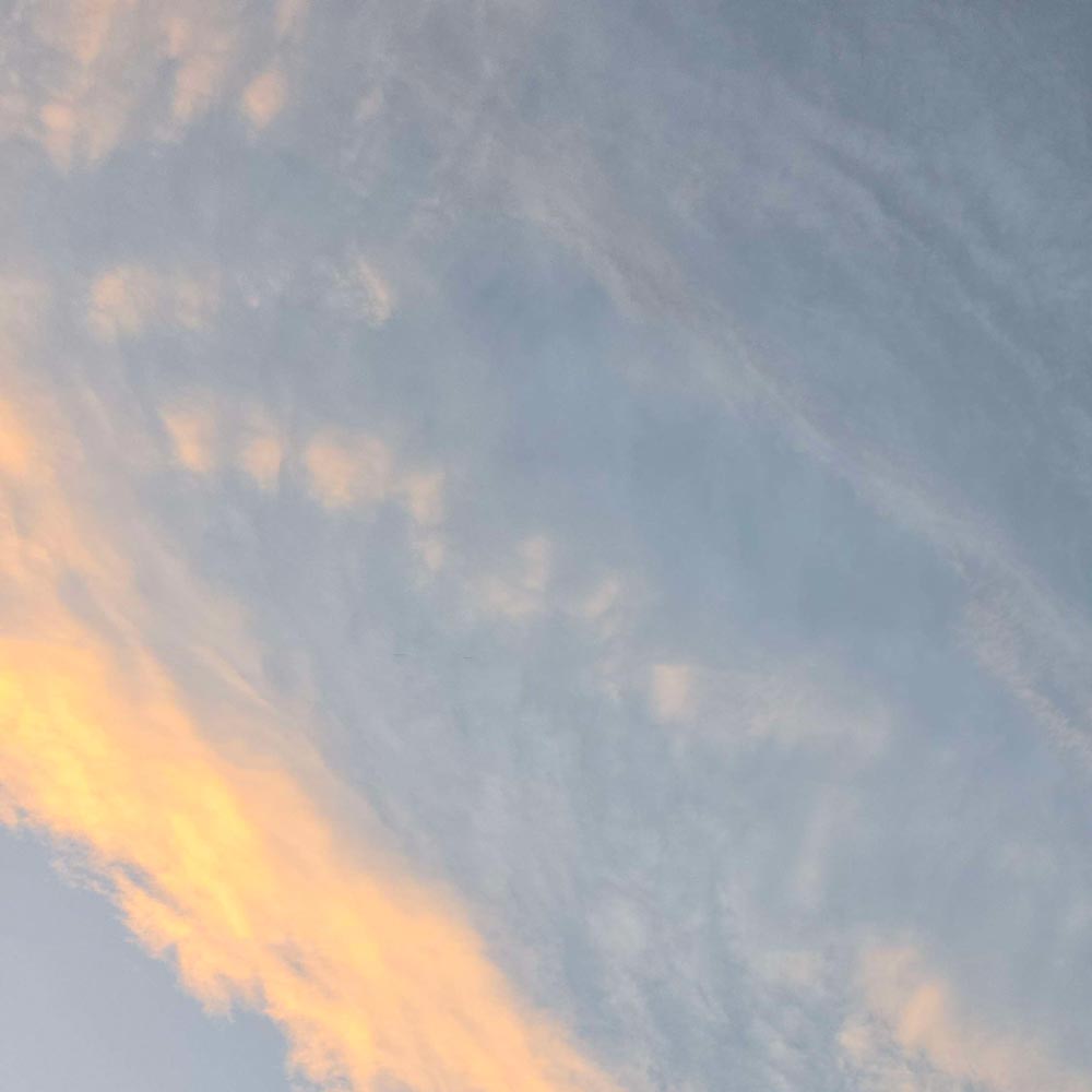 partly cloudy sky with peachy wispy clouds at sunset